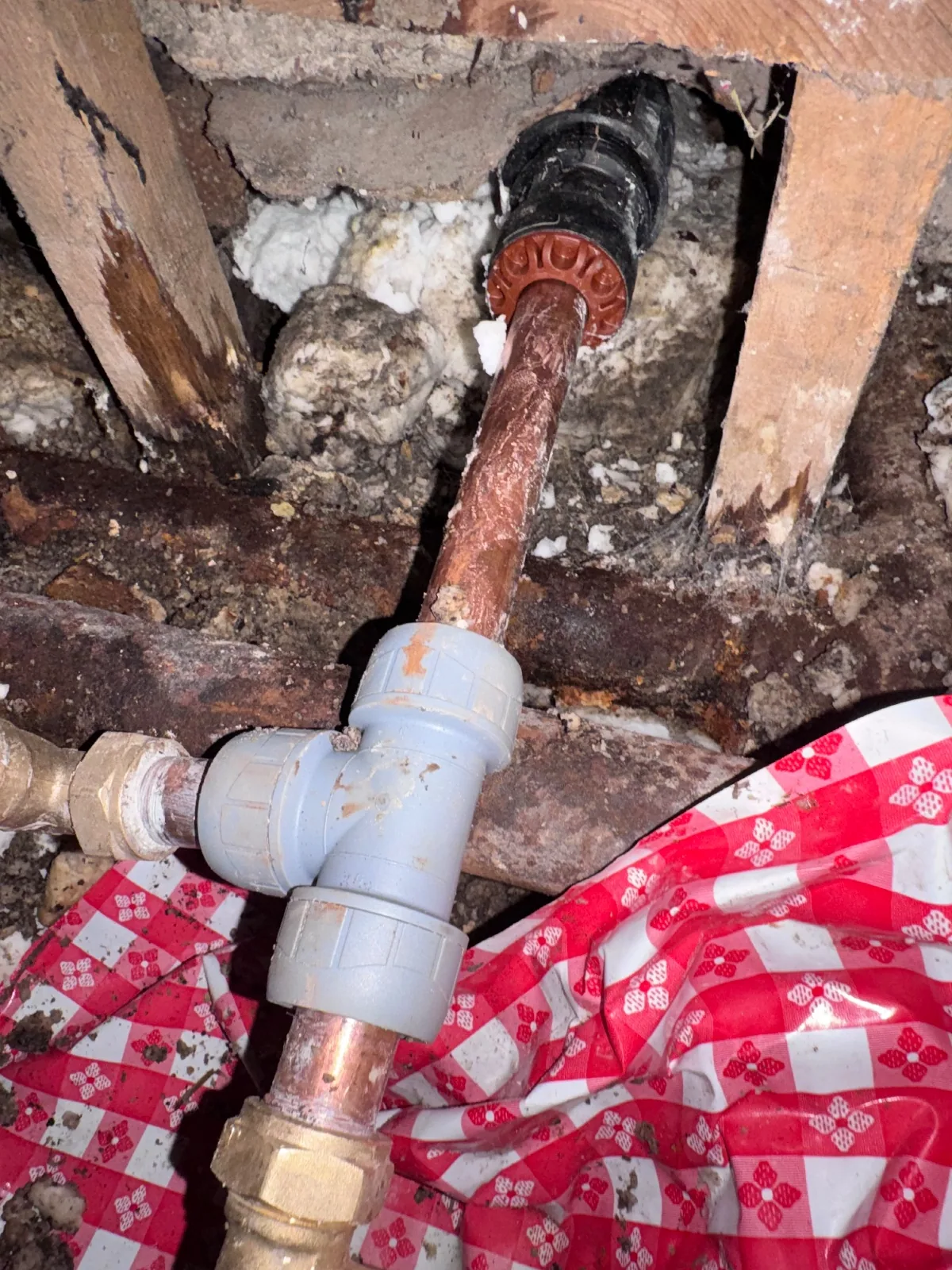 Pipe joint exposed beneath lifted floorboards